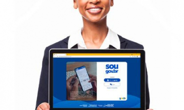 Imagem de uma mulher negra, cabelos curtos, sorrindo e segurando um notebook, em cuja tela aparece a página Sougov.br