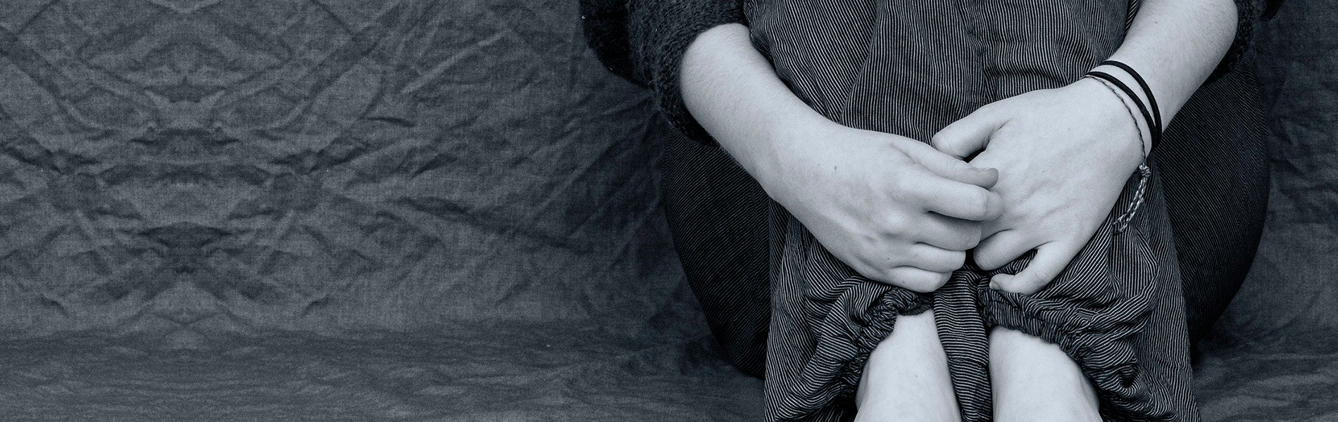 Foto em preto e branco de pessoa abraçando as próprias pernas