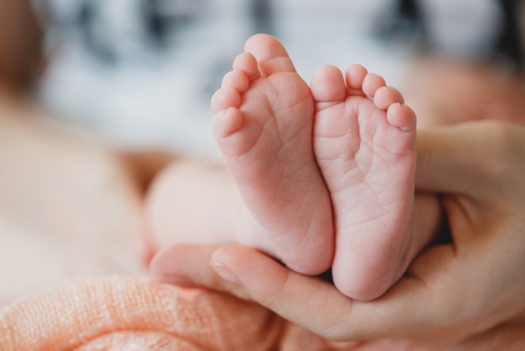 imagem da mão de uma pessoa segurando os pés de um recém-nascido