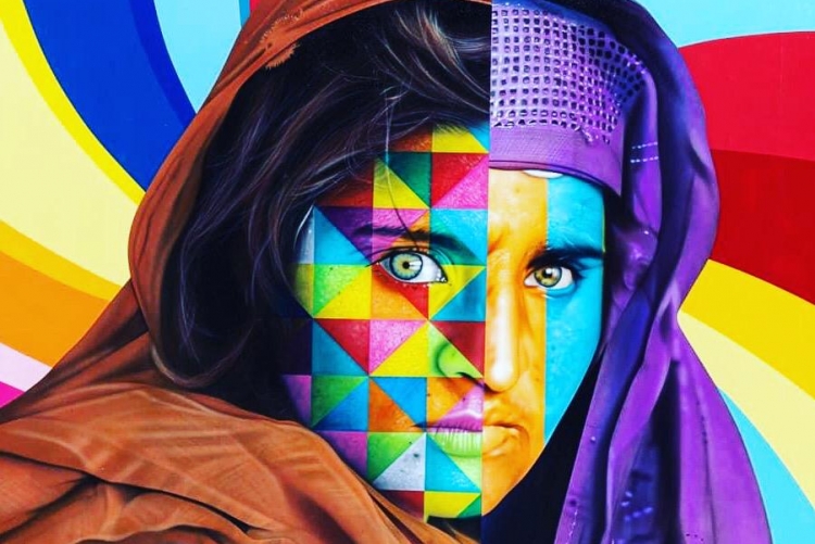 Mulher muçulmana usando lenço em volta do rosto pintada de muitas cores.