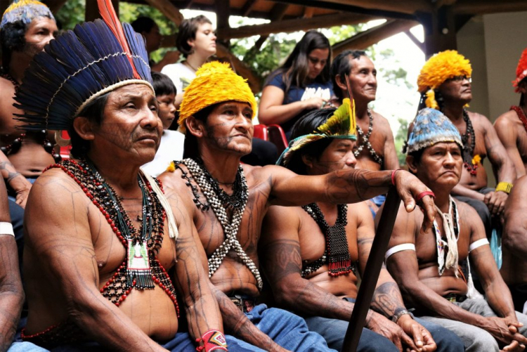 Indígenas da etnia Munduruku, localizada no Pará, durante mobilização em Brasília. #ParaTodosVerem Um grupo de indígenas do povo Munduruku, alguns sentados e outros em pé, utilizam acessórios tradicionais e pinturas típicas do seu povo.