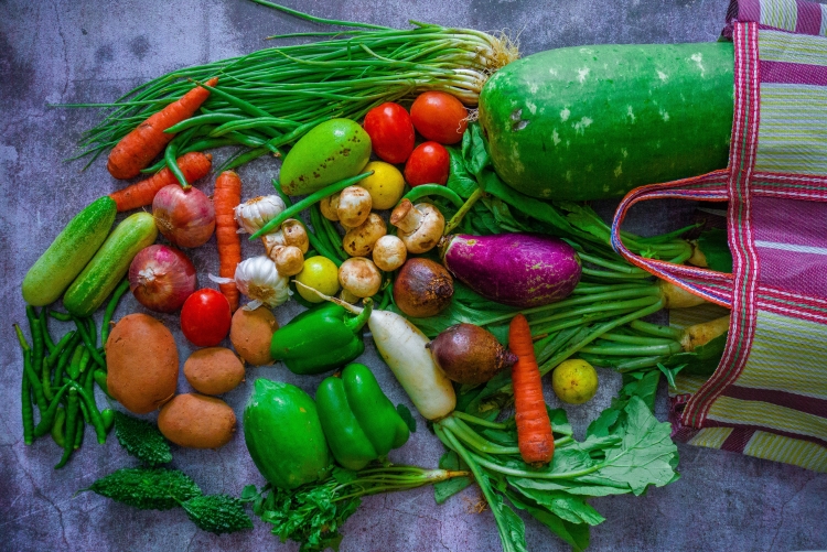 Legumes coloridos em cima de uma superfície saindo de uma sacola de feira