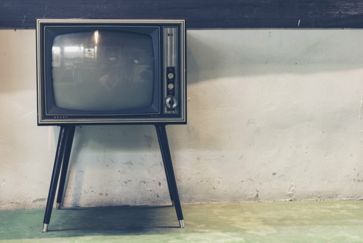Tv analógica com pés de madeira localizados no canto esquerdo da foto