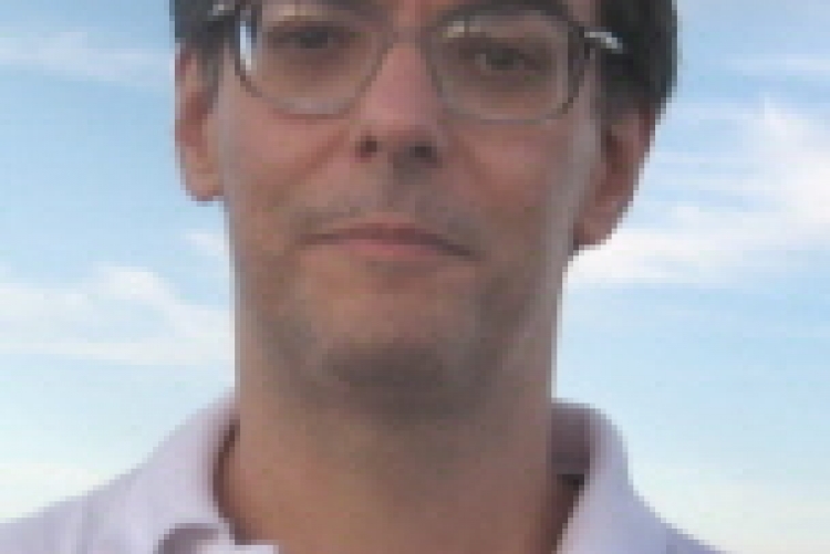 foto do professor Fábio, com fundo azul, homem branco, cabelos castanhos curtos e óculos