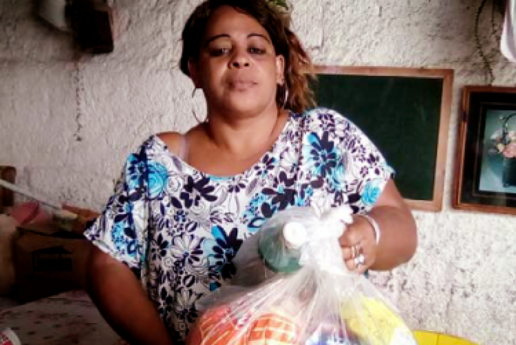 Foto de mulher segurando saco plástico contendo alimentos não perecíveis