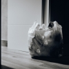 Foto de sacola de plástico cheia de lixo ao lado de uma porta aberta