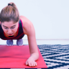 Mulher realizando exercício de "prancha" sobre tapete de yoga