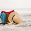 areia da praia, um par de chinelos, óculos de sol e chapéu de palha