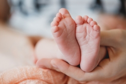 imagem da mão de uma pessoa segurando os pés de um recém-nascido