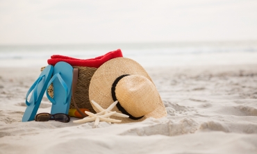areia da praia, um par de chinelos, óculos de sol e chapéu de palha