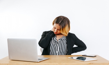 imagem: mulher em frente ao computador com mãos sobre a nuca e testa franzida