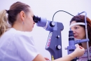 Médica examina visão de paciente através de um equipamento oftalmológico