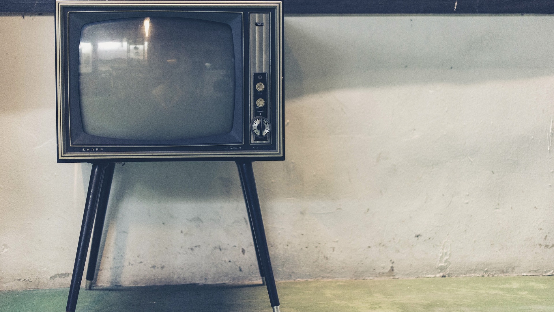 Tv analógica com pés de madeira localizados no canto esquerdo da foto