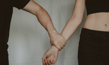 Foto em close up mostrando um braço masculino segurando uma mulher pelo pulso