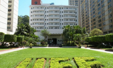 gramado verde em primeiro plano, ao fundo um prédio branco com um letreiro azul escrito uff