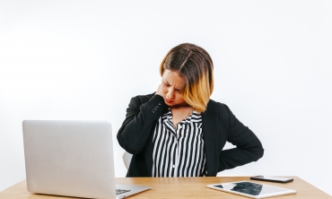 imagem: mulher em frente ao computador com mãos sobre a nuca e testa franzida