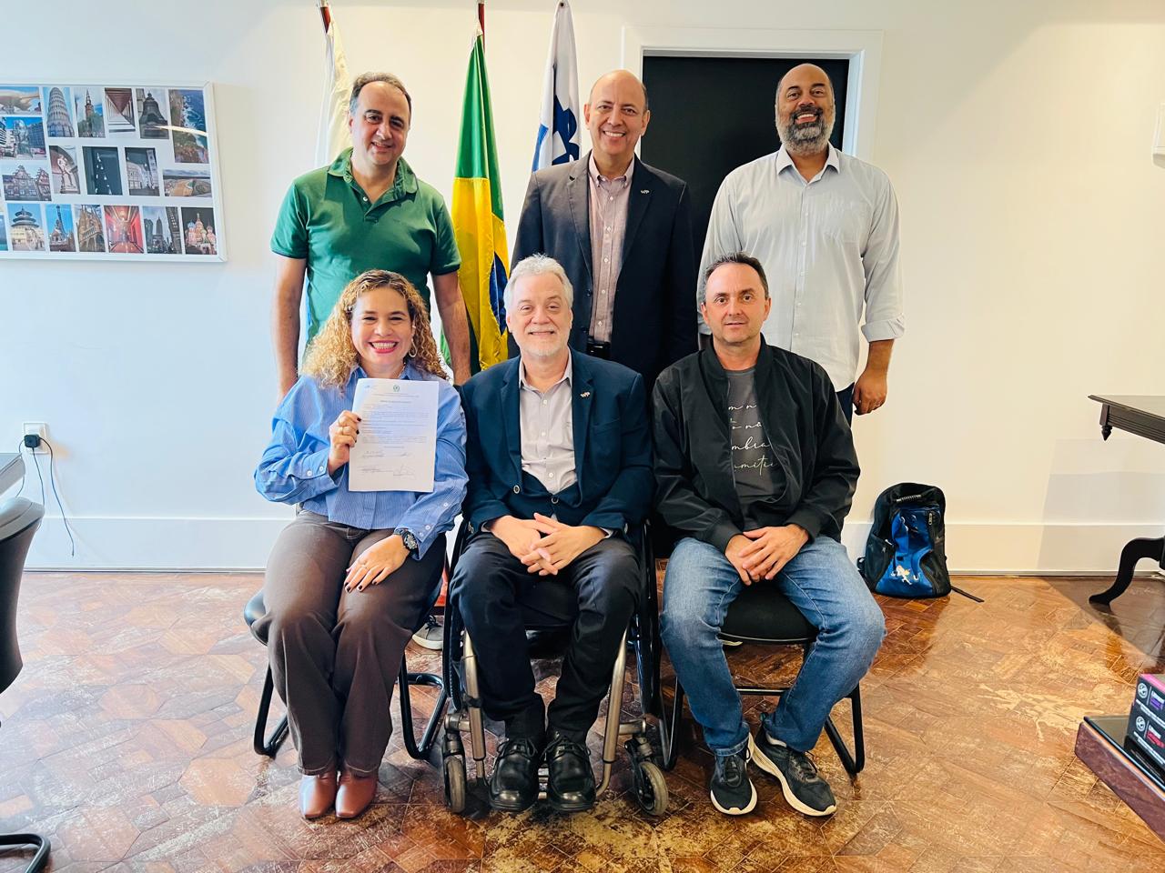 Autoridades posam para foto em frente à bandeira nacional