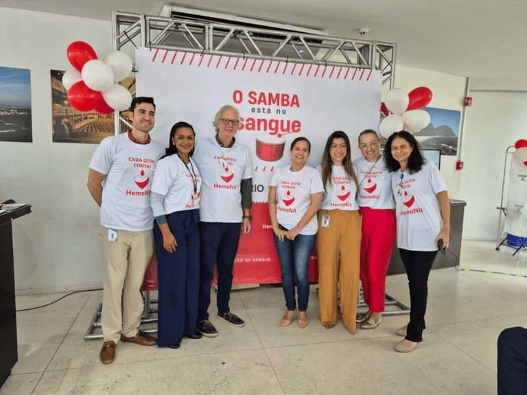 Foto de um grupo de pessoas em frente a cartaz