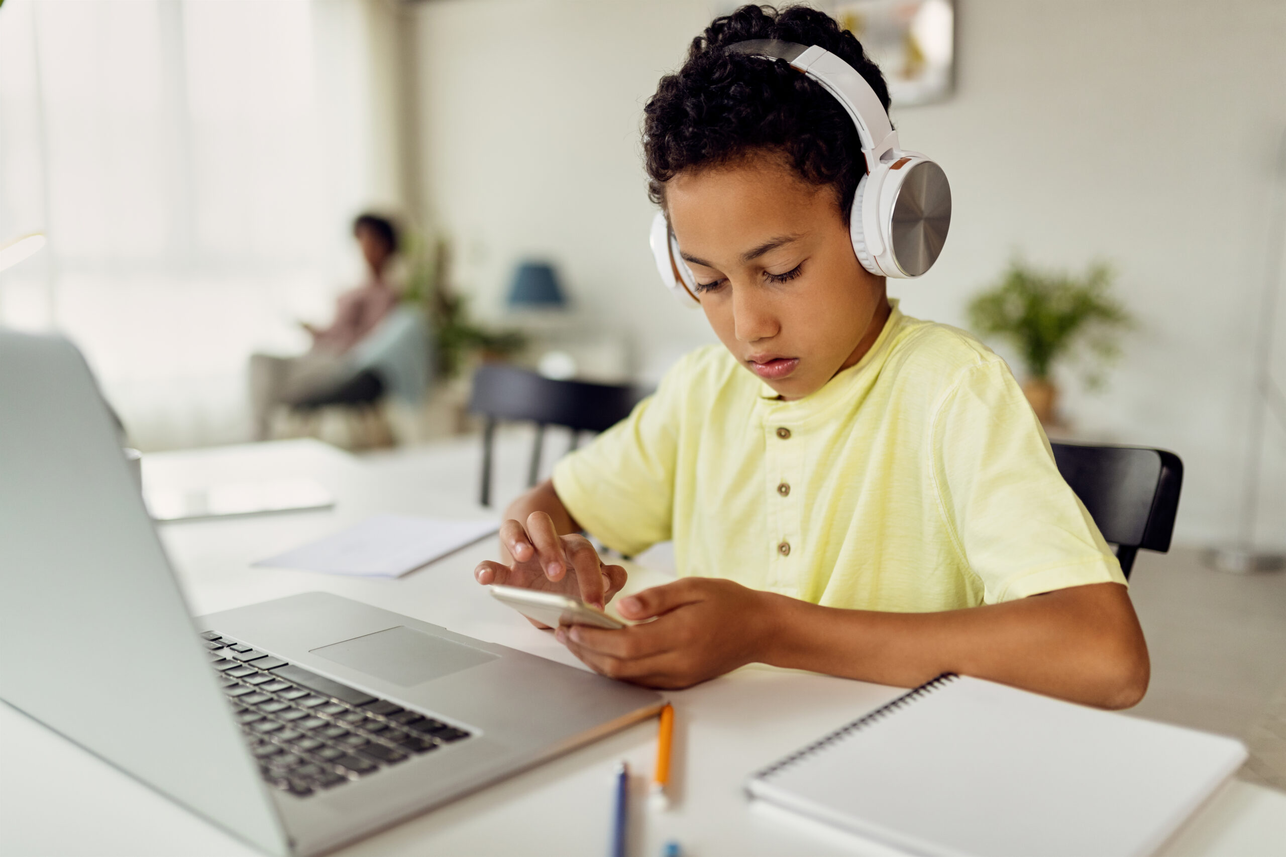 African American boy using smart phone while learning at home.